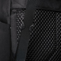 Primer plano de la correa de una mochila negra y el panel trasero texturizado