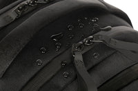 Primer plano de una mochila negra con cremalleras y correas sobre fondo blanco