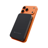 A black Hyper portable power bank attached to an orange smartphone, shown from a three-quarters perspective on a clean white background.