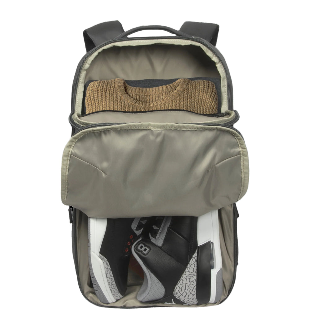 Mochila con un jersey y zapatos en su interior sobre fondo blanco